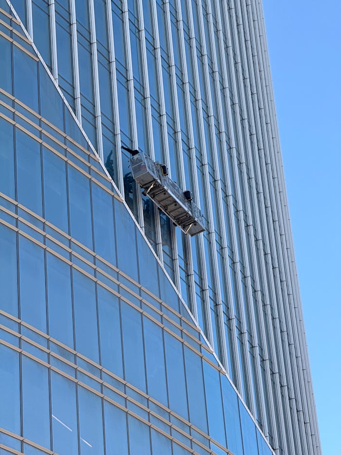 Professional window cleaners suspended on a high-rise building facade.